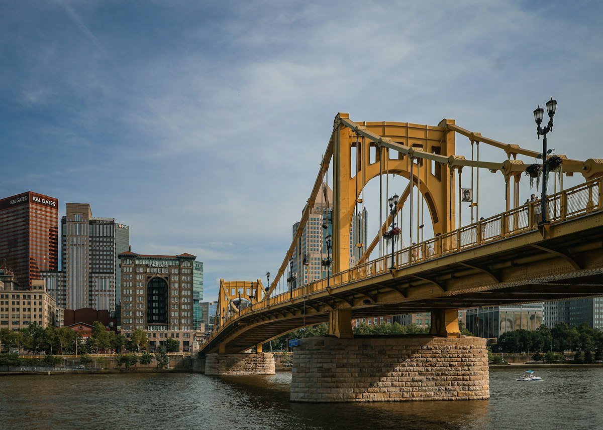 The yellow Roberto Clemente Bridge over the river with the Pittsburgh skyline
