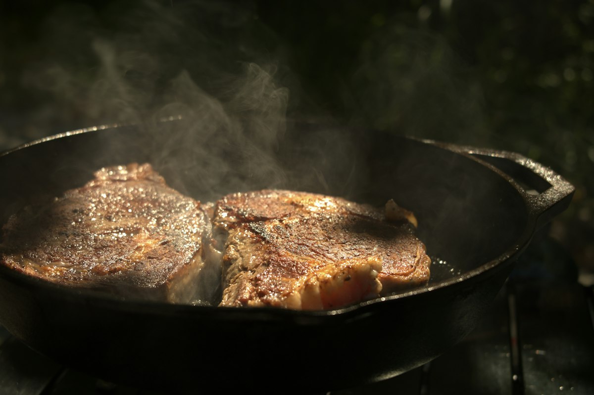 A steak searing in a skillet on the stove